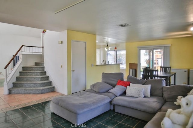 living room with dark tile patterned flooring, visible vents, and stairway