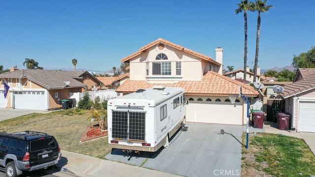 mediterranean / spanish-style home with a garage, concrete driveway, a tiled roof, a front yard, and stucco siding