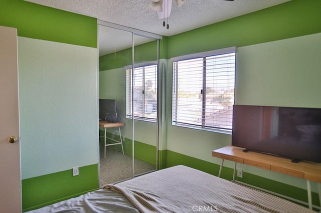 carpeted bedroom with a ceiling fan, a closet, and a textured ceiling