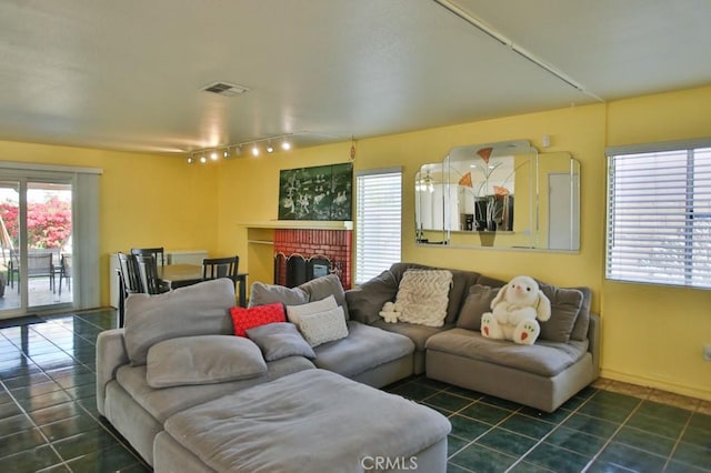 living room featuring dark tile patterned floors, plenty of natural light, a fireplace, and visible vents