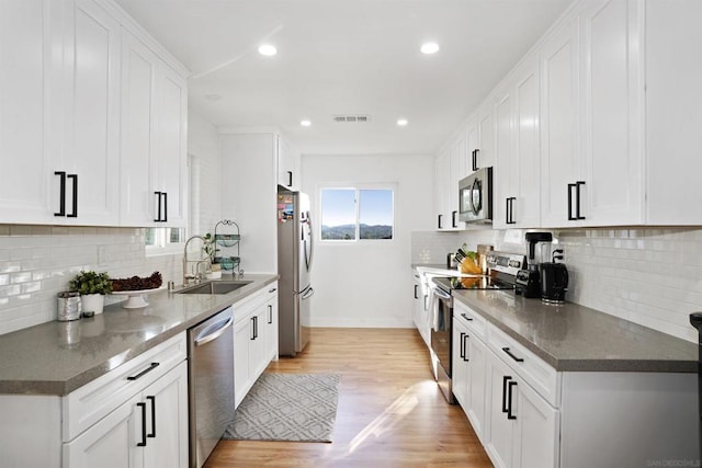 kitchen with sink, white cabinetry, appliances with stainless steel finishes, and light hardwood / wood-style flooring