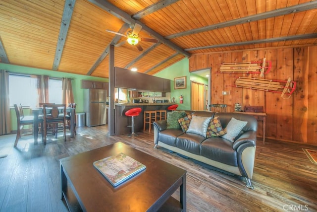 living room with wood-type flooring, wood walls, lofted ceiling with beams, ceiling fan, and wooden ceiling