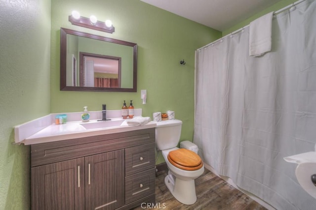 bathroom featuring hardwood / wood-style flooring, curtained shower, toilet, and vanity