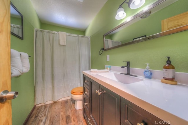 bathroom featuring toilet, a shower with shower curtain, hardwood / wood-style floors, and vanity