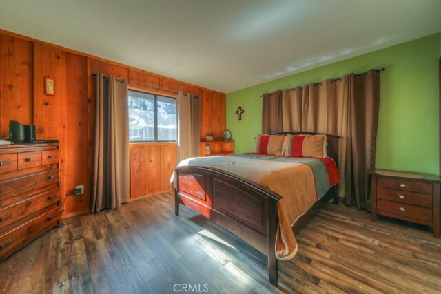 bedroom featuring dark hardwood / wood-style floors and wooden walls