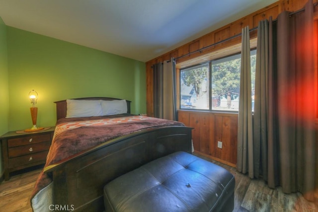 bedroom with wood-type flooring and wood walls