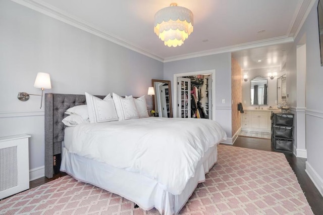 bedroom with hardwood / wood-style flooring, radiator, a spacious closet, connected bathroom, and a closet