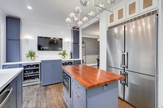 kitchen featuring dark hardwood / wood-style floors, a center island, built in appliances, butcher block counters, and beverage cooler