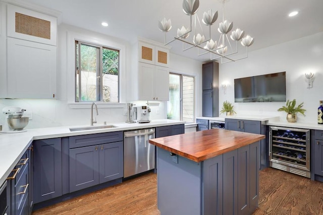 kitchen featuring pendant lighting, sink, a center island, white cabinets, and stainless steel dishwasher