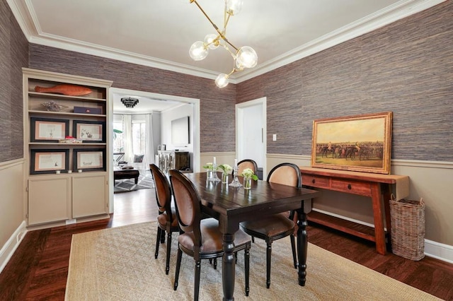 dining space featuring wood-type flooring, ornamental molding, and a notable chandelier