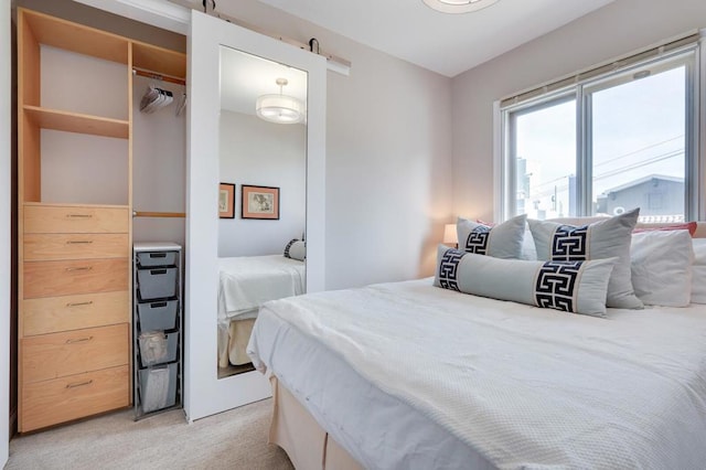 bedroom with a barn door and light carpet