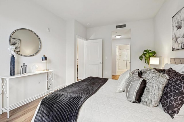 bedroom with connected bathroom and hardwood / wood-style floors