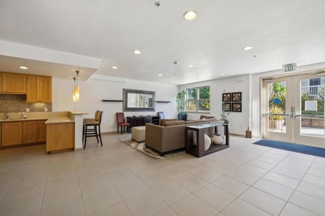 tiled living room featuring french doors and sink