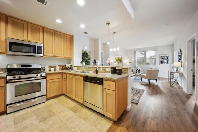 kitchen featuring hanging light fixtures, appliances with stainless steel finishes, sink, and kitchen peninsula