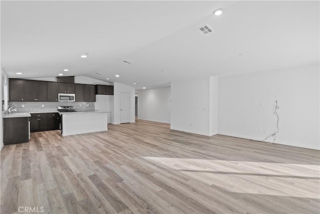 unfurnished living room featuring lofted ceiling, light wood-type flooring, and sink