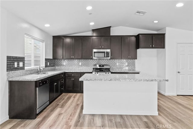 kitchen with appliances with stainless steel finishes, a center island, light wood-type flooring, lofted ceiling, and sink