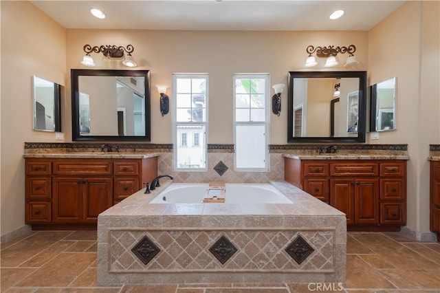 bathroom featuring tiled tub and vanity