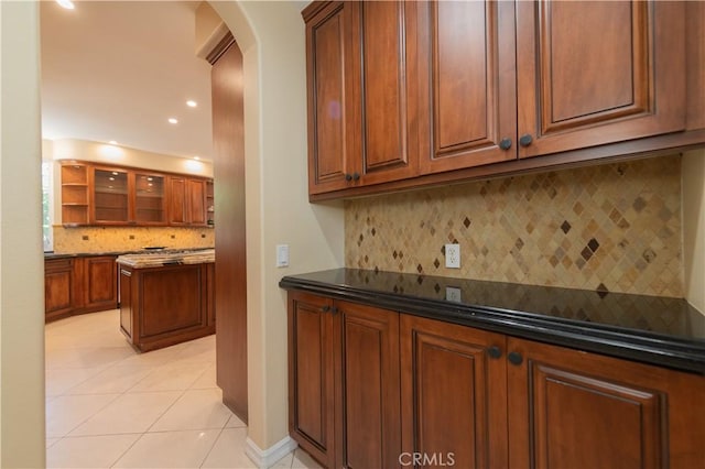 bar featuring light tile patterned floors, decorative backsplash, and dark stone countertops