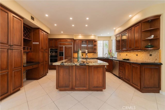 kitchen with light tile patterned floors, stainless steel appliances, backsplash, dark stone countertops, and a kitchen island