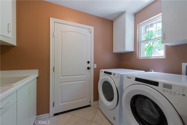 laundry area featuring cabinets, light tile patterned floors, sink, and washing machine and clothes dryer