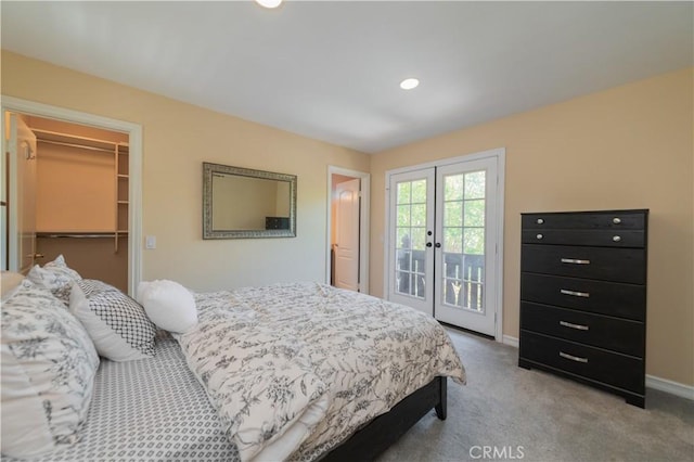 bedroom with light colored carpet, a closet, a spacious closet, and access to exterior