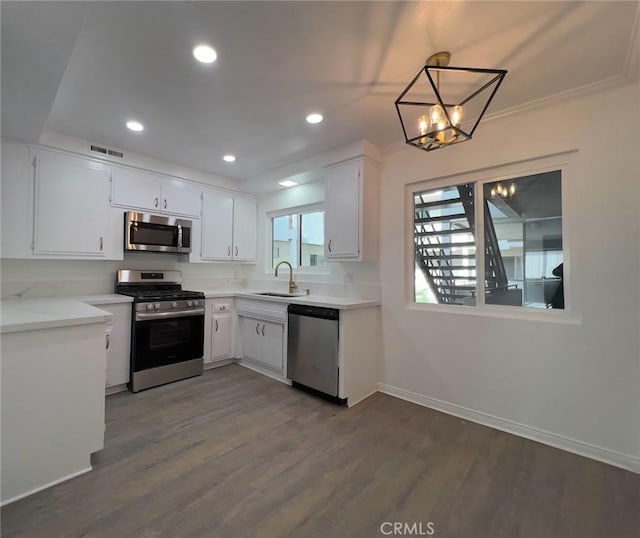 kitchen featuring decorative light fixtures, white cabinetry, stainless steel appliances, sink, and a chandelier