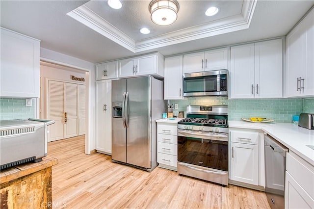 kitchen featuring a tray ceiling, stainless steel appliances, and white cabinetry