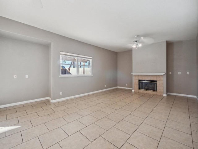 unfurnished living room with ceiling fan, light tile patterned flooring, and a tiled fireplace