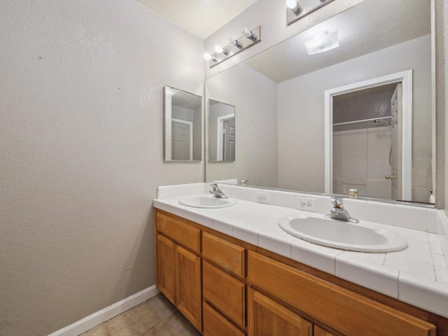 bathroom featuring tile patterned flooring, walk in shower, and vanity