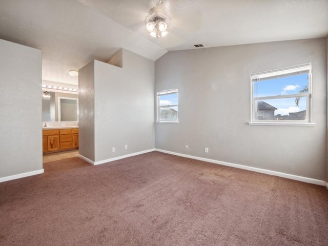 unfurnished bedroom with ceiling fan, carpet flooring, lofted ceiling, and connected bathroom