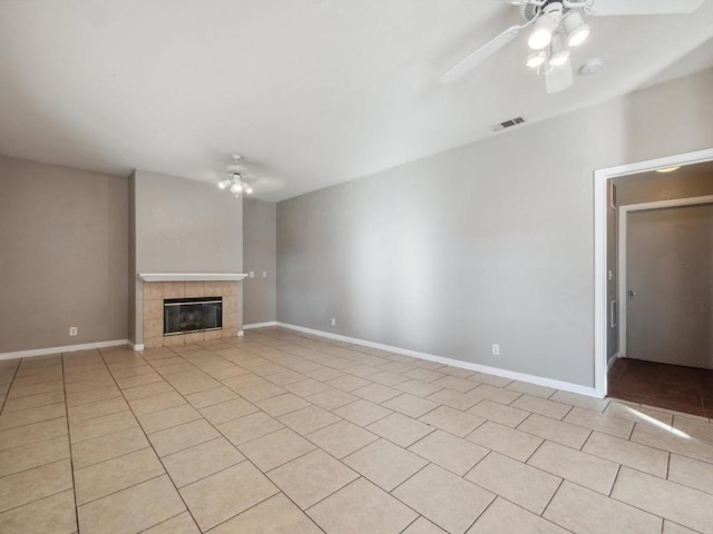 unfurnished living room featuring ceiling fan, light tile patterned floors, and a tiled fireplace