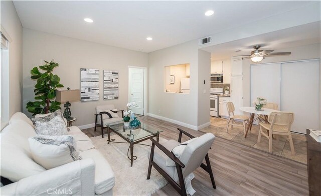 living room with ceiling fan and light wood-type flooring