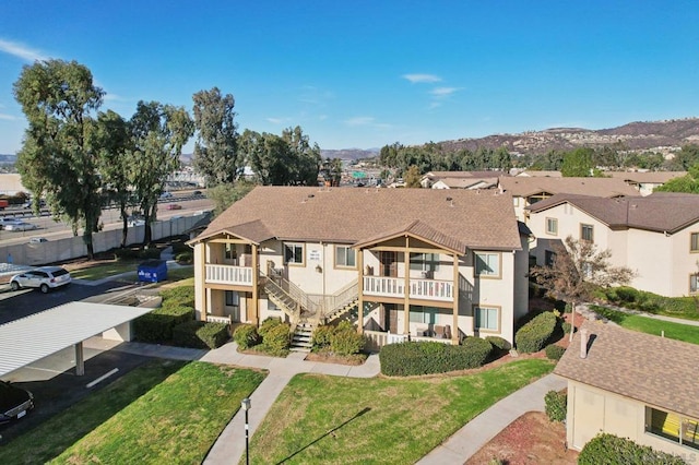 exterior space with a balcony, a yard, and a mountain view