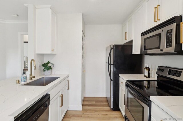 kitchen with appliances with stainless steel finishes, sink, light stone counters, and white cabinetry