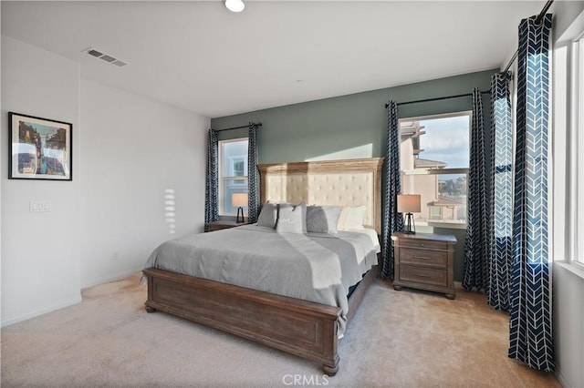 bedroom with light colored carpet and multiple windows