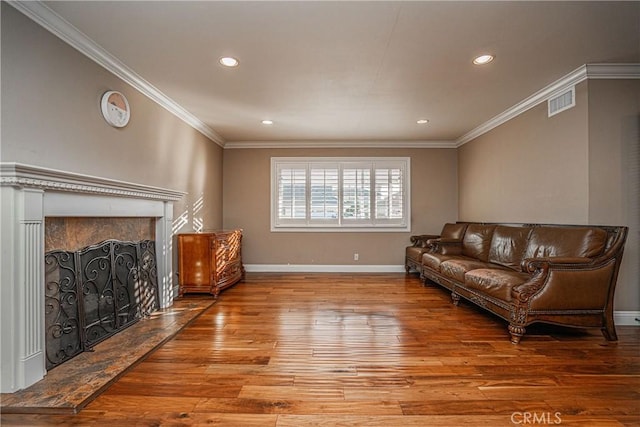 living room featuring crown molding, a fireplace, and hardwood / wood-style floors