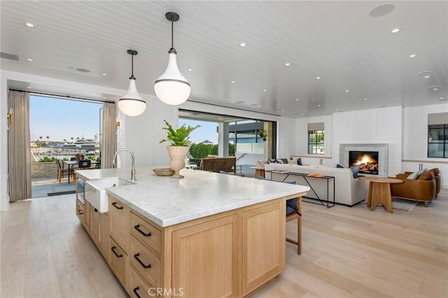 kitchen with light hardwood / wood-style flooring, sink, light brown cabinets, and pendant lighting