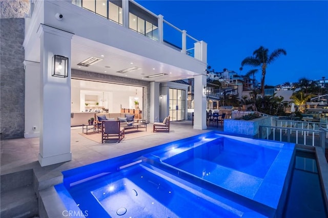 pool at night featuring an in ground hot tub and a patio