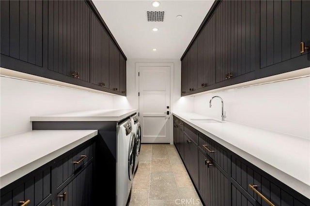 clothes washing area featuring sink, separate washer and dryer, and cabinets