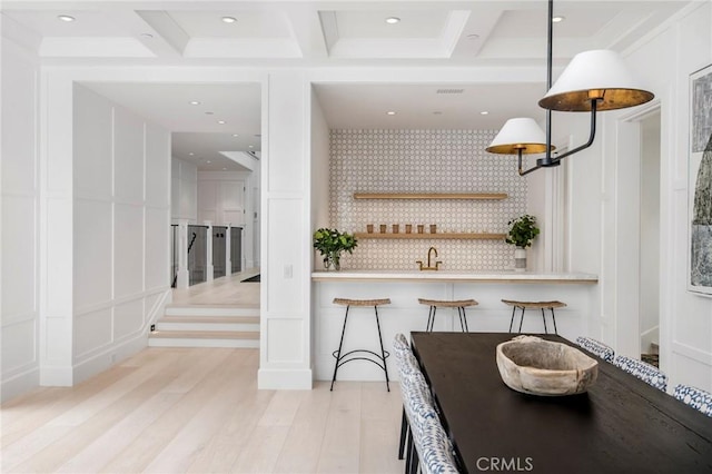 interior space with light wood-type flooring, sink, coffered ceiling, and beamed ceiling