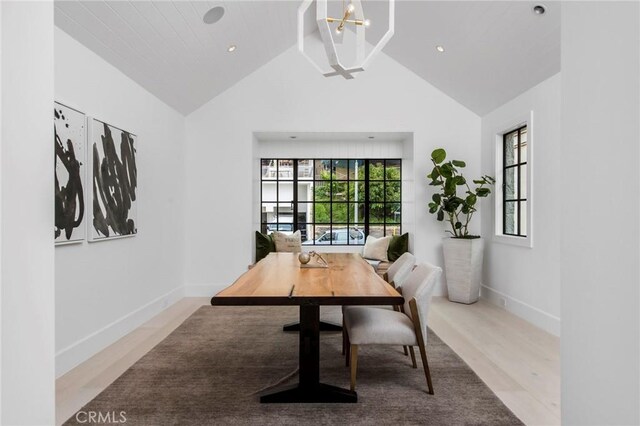 dining area with vaulted ceiling with beams, light wood-type flooring, and an inviting chandelier