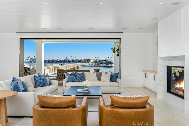 living room featuring a water view, light wood-type flooring, and a fireplace