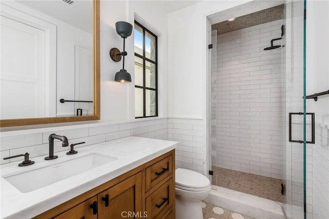 bathroom featuring a shower with shower door, tile walls, toilet, and vanity