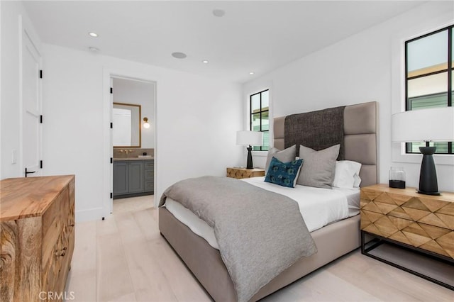 bedroom with ensuite bath and light wood-type flooring