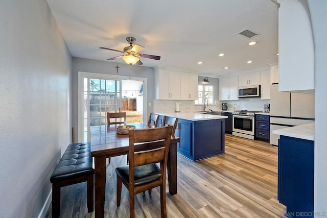 kitchen featuring white fridge, a healthy amount of sunlight, stainless steel range oven, white cabinets, and blue cabinets