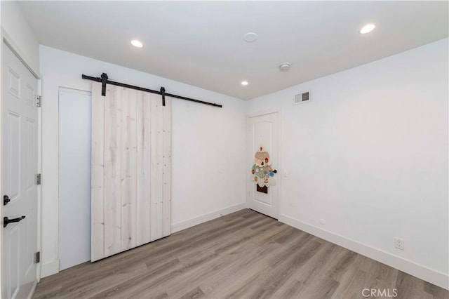 empty room with a barn door and light hardwood / wood-style floors