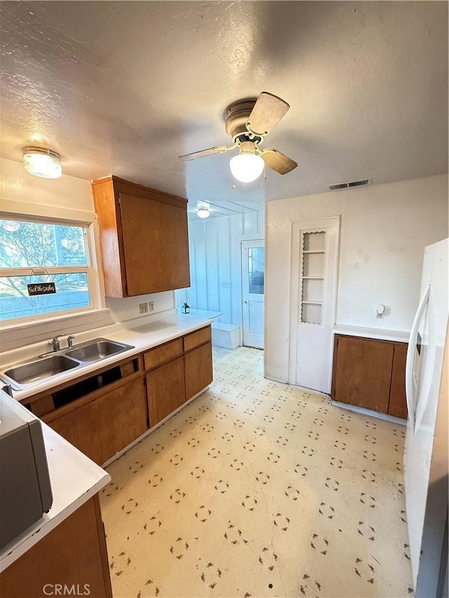 kitchen with white refrigerator, sink, a textured ceiling, and ceiling fan