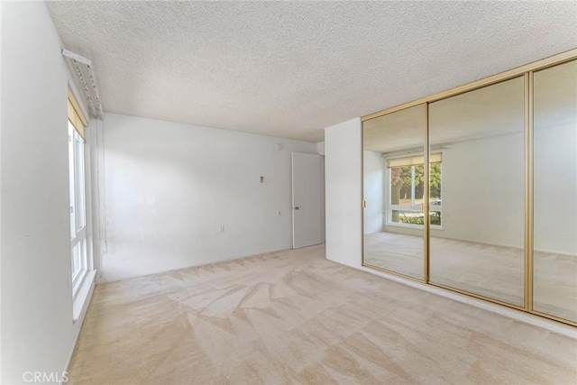 unfurnished bedroom with a closet, light colored carpet, and a textured ceiling