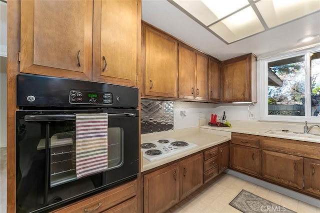 kitchen featuring tasteful backsplash, black oven, sink, and white cooktop