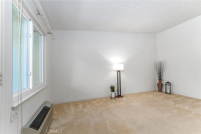 spare room with a textured ceiling, light carpet, and a wall unit AC